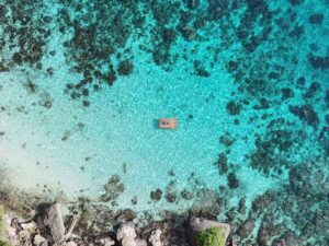 Beste Sehenswürdigkeiten auf Siquijor – Luftaufnahme von türkisfarbenem Wasser mit kleinem Holzfloß vor der Küste