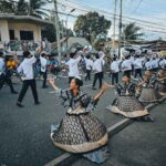 Siquijor Fiestas street parade with locals in white and gold costumes dancing on a sunny day