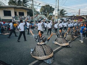 Siquijor Fiestas street parade with locals in white and gold costumes dancing on a sunny day
