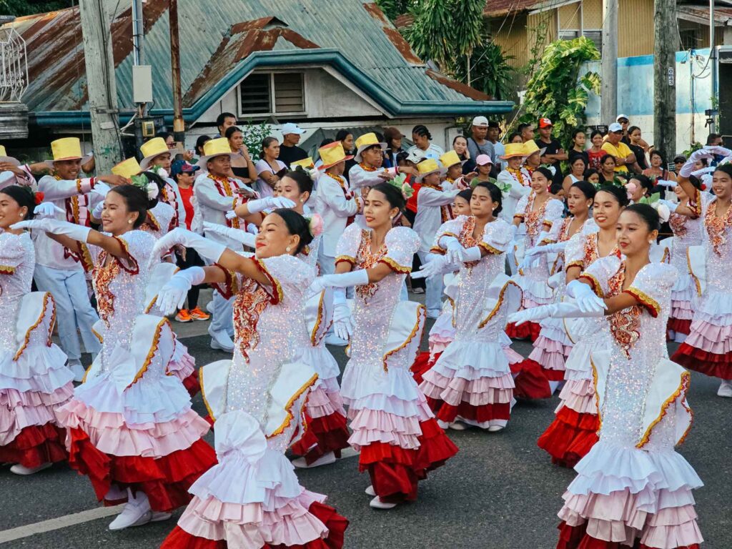 Women in white traditional outfits dancing joyfully on the street during a Siquijor fiesta